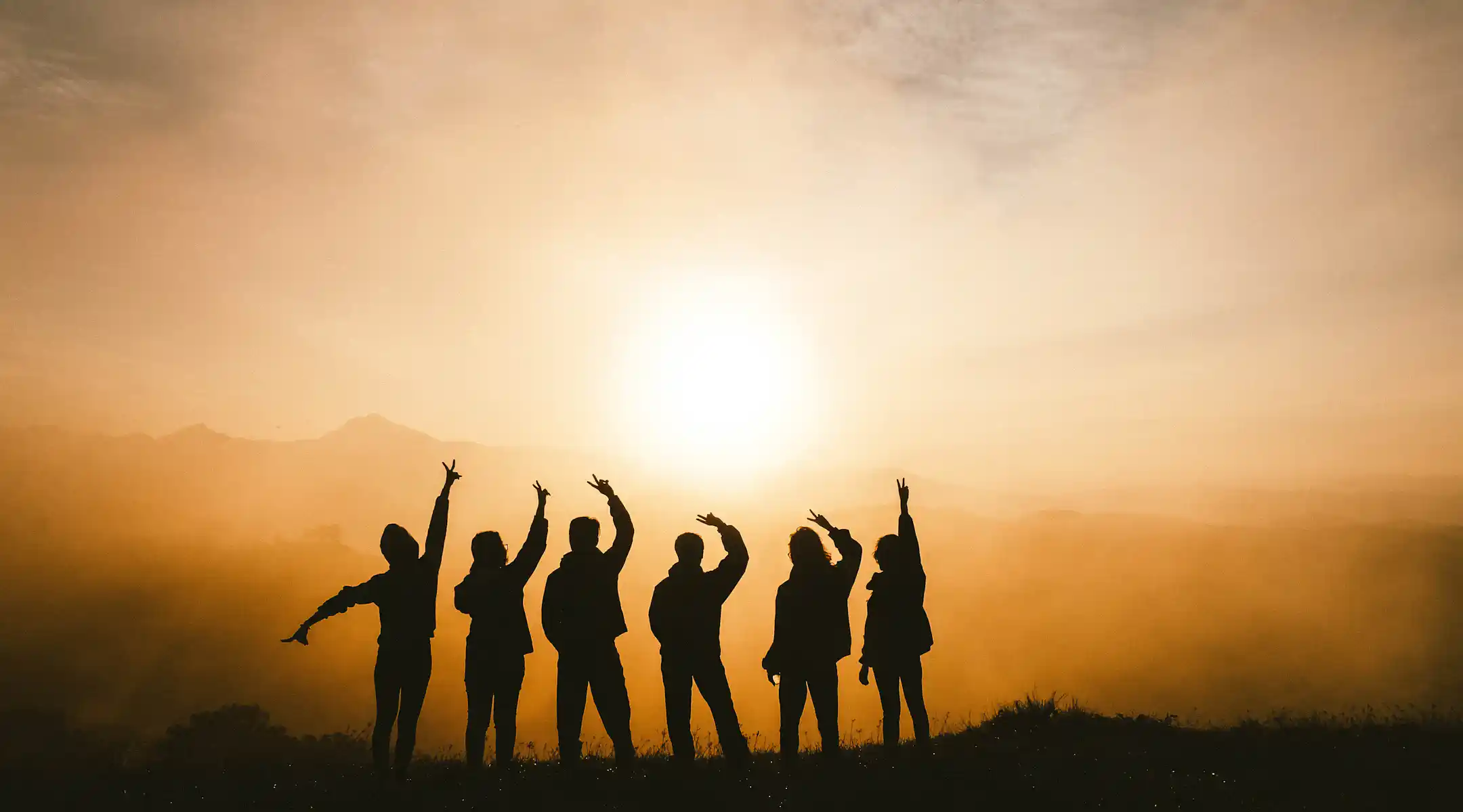 Image of Group in Sunset with Hands Lifted in Accomplishment